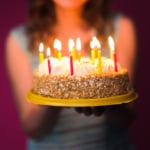 Hands of young woman holding birthday cake selective focus.