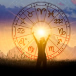 A woman reaching toward a zodiac wheel centered upon the Sun.